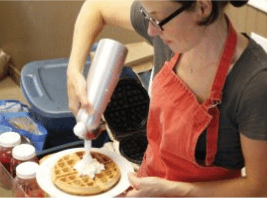 Emily adding whipped cream to a waffle