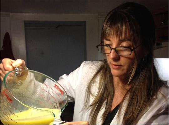 woman in lab coat pouring yellow liquid