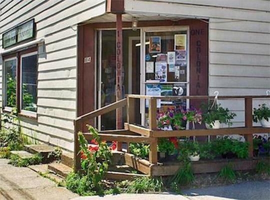 the outside of a store with plants covering the porch 