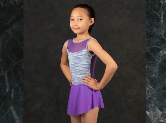 young girl with pony tail wearing purple athletic leotard with a skirt