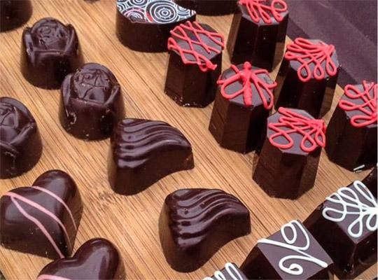 various chocolates with decorative designs set out on a wooden board