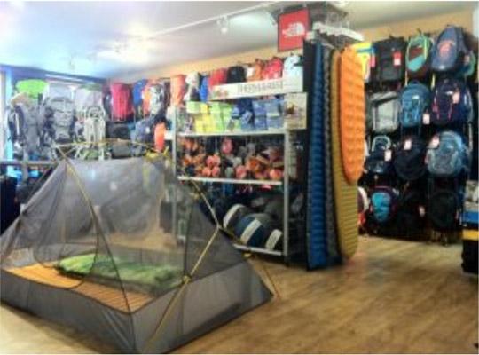 a shop floor with a tent in front of sleeping backs and backpacks