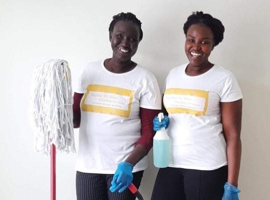 Two Together We Shine Employees smiling with a mop and spray cleaner