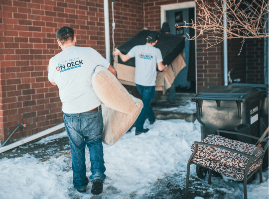 two men moving furniture into a home 