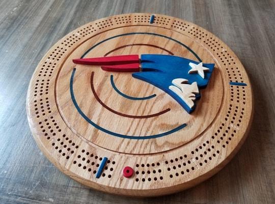 round wooden crib board designed with a superhero wing in the middle