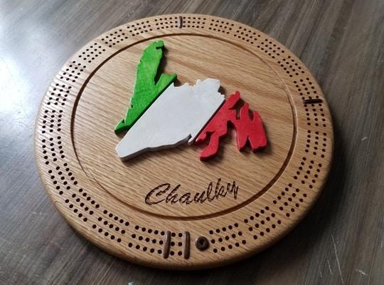 round wooden crib board designed with a tri colour island of Newfoundland in the middle with the name Chaulky