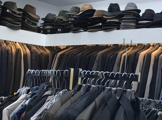 hats stacked on shelves around a room full of mens sport coats