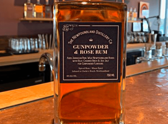 bottle of The Newfoundland Distillery Company Award-Winning Gunpowder & Rose Rum.  beautiful clear amber colour in rectangular rippled glass with a green label