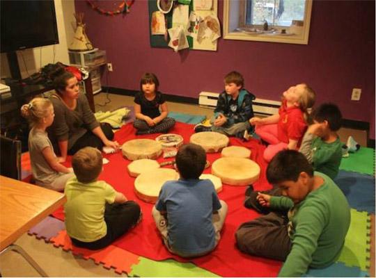 a group of children sitting in a circle with drums in the middle