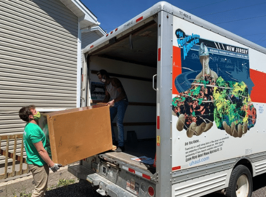 Home Again volunteers moving a dresser into a moving van.  