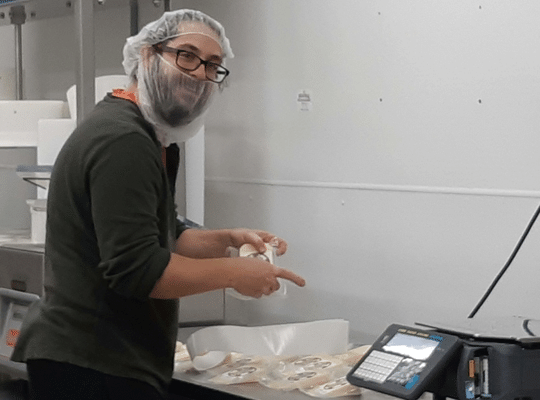 a happy young man wrapping cheese at Five Brothers Artisan Cheese, Goulds