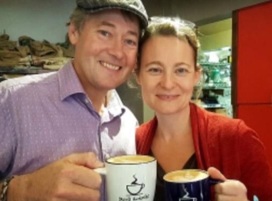 smiling man and woman holding mugs of coffee