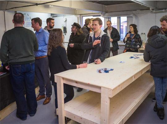 a group of people gathered around a wooden table at the tool library