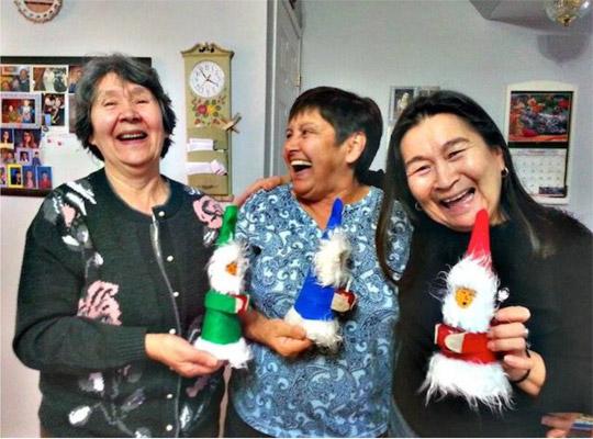 a group of people smiling and laughing holding hand made dolls