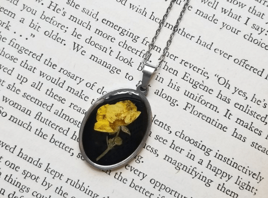 Artisan Velvet Snow Pressed Buttercup necklace on the page of the book 