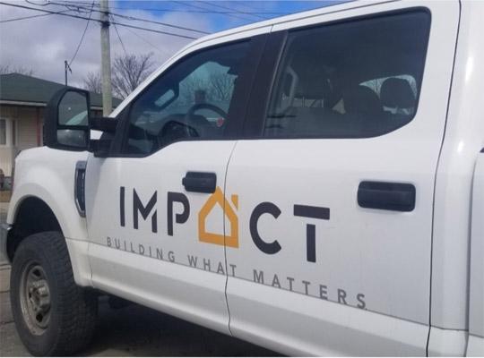 side of a white pick up truck with impact construction logo