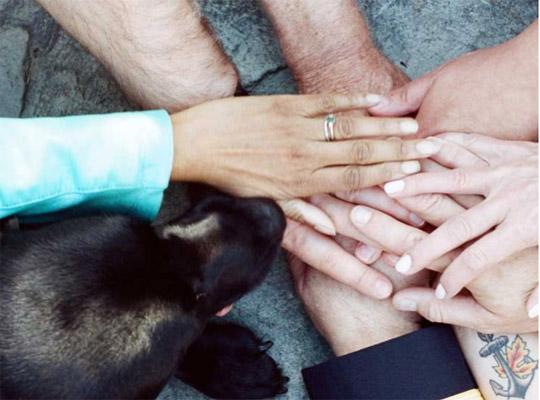 a group of people holding hands and a dog 