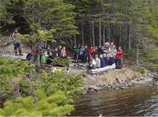 students standing by the waterside in the woods taking part in an activity