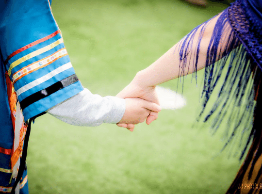 two people in indigenous dress holding hands